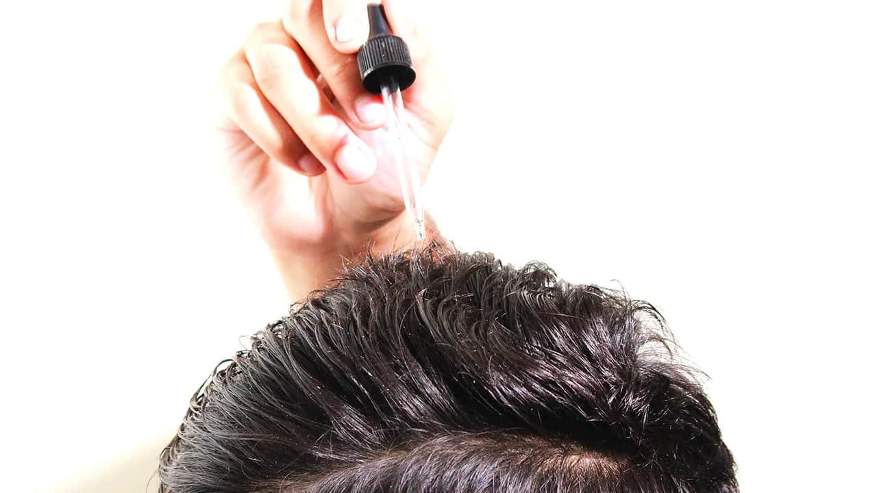 a man applying oil on his hair